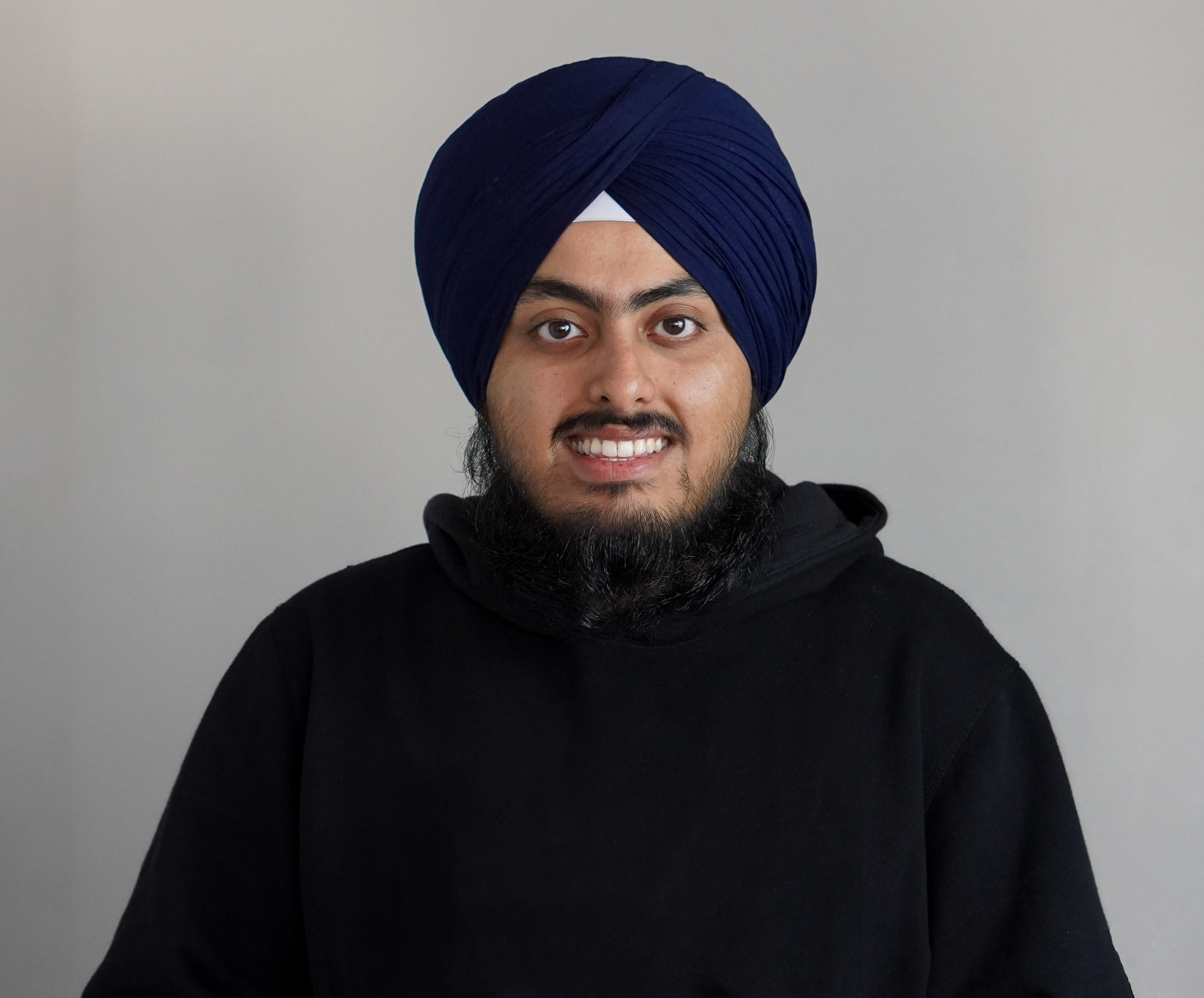 Joravar Singh Punia smiling in a black hoodie and blue turban